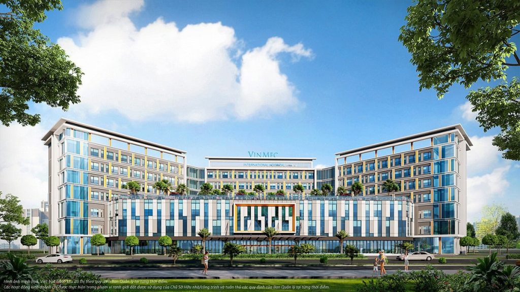 Vinhomes Hòa Long Bắc Ninh 13 Phối cảnh bệnh viện Vinmec tại Vinhomes Hòa Long - Bắc Ninh, với tòa nhà hiện đại, mặt tiền kính lớn, không gian xanh xung quanh, và cư dân đi bộ trên đường.